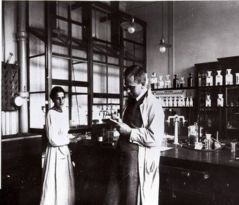 Lise Meitner and Otto Hahn in the Berlin laboratory in 1913. Source: MPG Berlin-Dahlem archive Two scientists in lab coats working in a laboratory with glassware and chemicals.