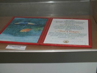 Paul Crutzen's Nobel Prize certificate. Photo: Susanne Benner Red-framed certificate and a painting are exhibited side by side in a glass case, highlighting an official recognition.