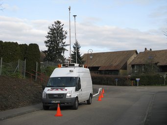 The mobile aerosol research laboratory enables measurements under real environmental conditions. In the Upper Black Forest and Alsace, researchers from the Max Planck Institute for Chemistry carried out extensive emission and immission measurements at and in the vicinity of wood-burning facilities. Mobile research laboratory vehicle (MoLa) belonging to the MPI for Chemistry, parked at the side of the road in a residential area, secured with traffic cones (orange).