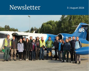 A group of people stands near a small aircraft at an airfield, with trees in the background.